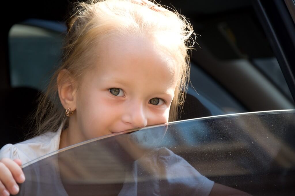 child looking out tinted car window